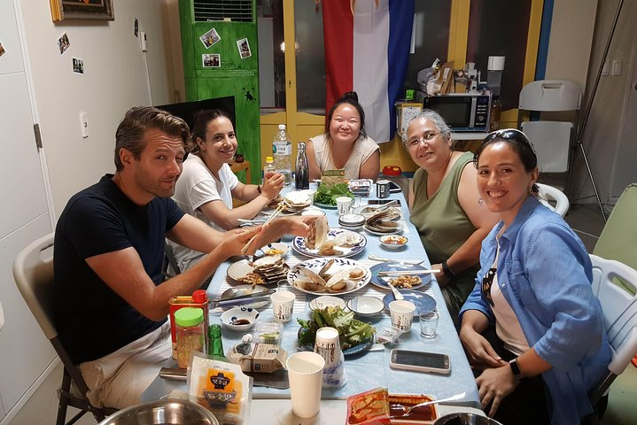 Savor the unique flavors of Busan's seafood with locals enjoying oysters and traditional dishes while sharing stories and laughter in a cozy setting. A memorable culinary adventure awaits!